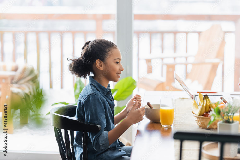 side view of happy african american girl having breakfast at home side view of happy african american girl having breakfast at home