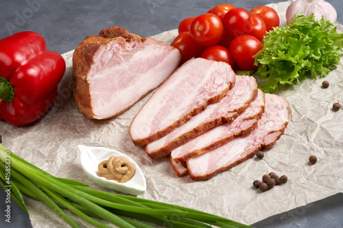 Traditional slicing of smoked pork on paper with tomatoes, onions and mustard. Classic meat products, delicacies.