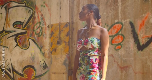 A young woman stands next to grafitti on a wall in an abandoned warehouse photo