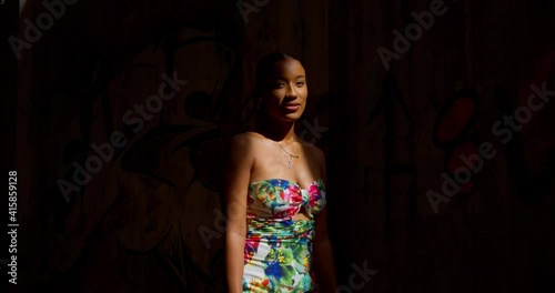 Fom darkness to light a young girl walks into the sunlight wearing a long dress photo