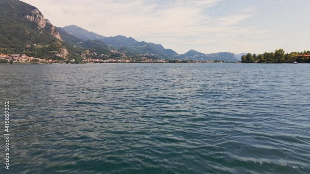Cinematic Flight Over The Blue Water Of Lake Como In Italy With Mountains And Cloudy Sky In Background - aerial drone shot Cinematic Flight Over The Blue Water Of Lake Como In Italy With Mountains And Cloudy Sky In Background - aerial drone shot