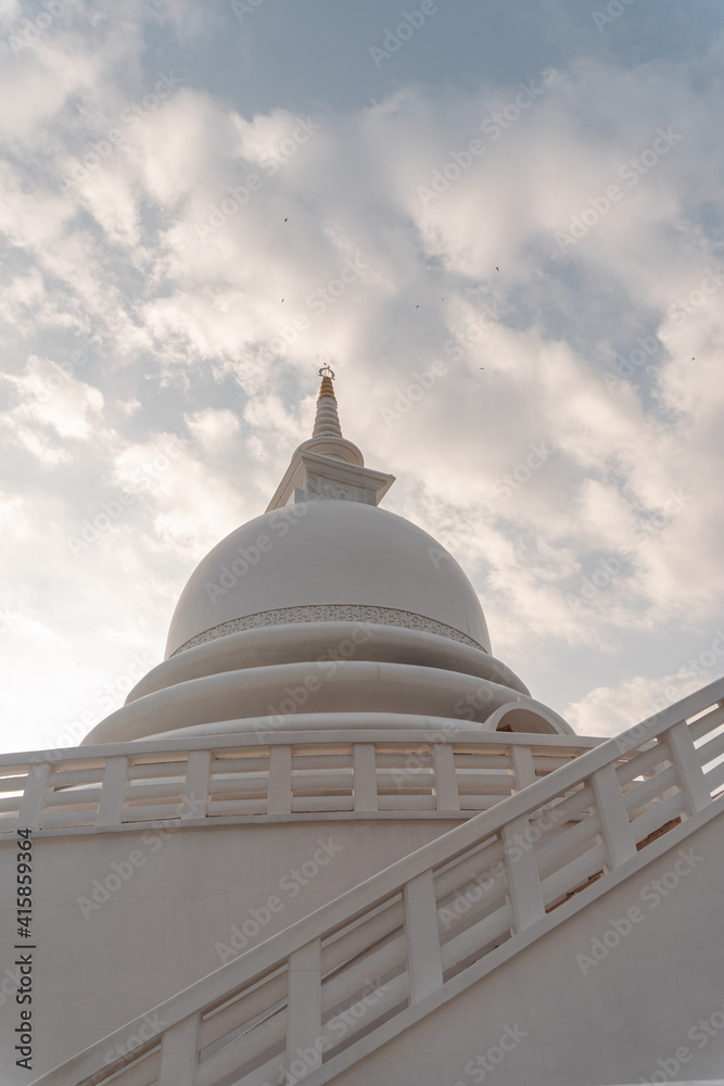 Piękna biała stupa, pagoda w świątynni buddyjskiej na tle nieba i zachodzącego słońca.
