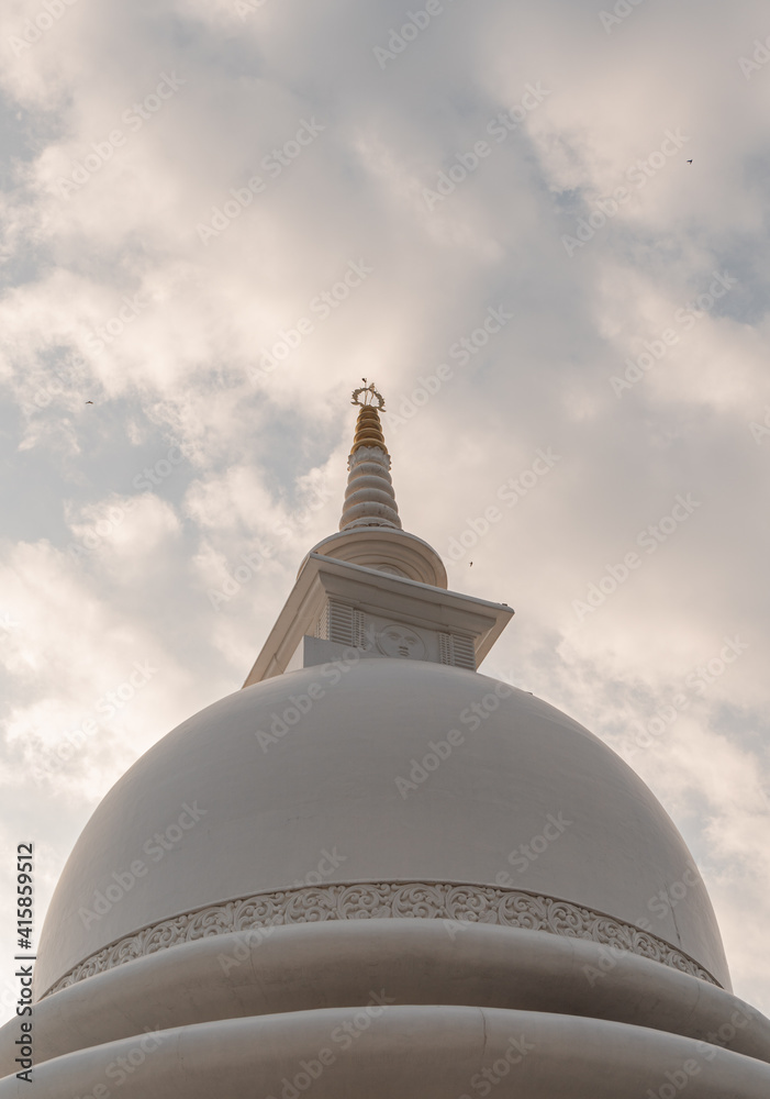Piękna biała stupa, pagoda w świątynni buddyjskiej na tle nieba i zachodzącego słońca.