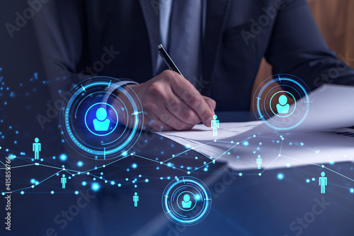 A potential employee in formal suit signing the contract to boost his career and gain new opportunities in personal growth. Concept of success. Hiring a new talented crew. Social media hologram icons photo