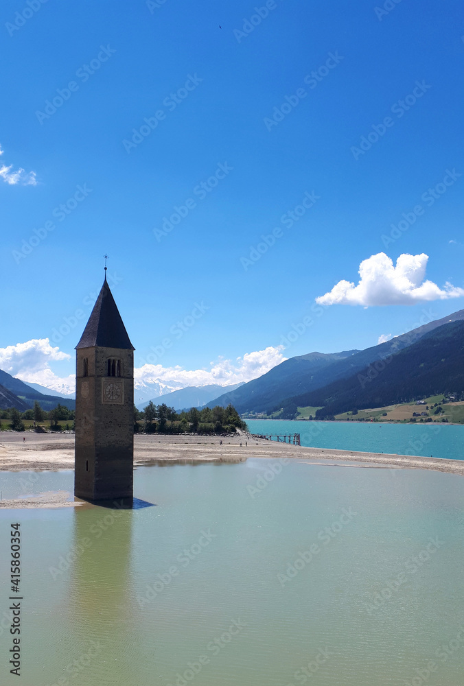der Glockenturm im Reschensee unter Wasser an einem Sommertag