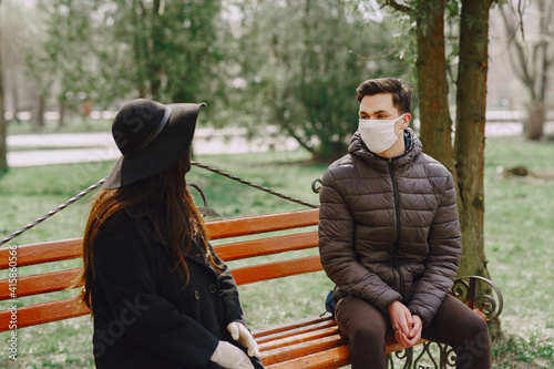 People in the city. Persons in a masks. Coronavirus theme. Couple sitting on a bench.