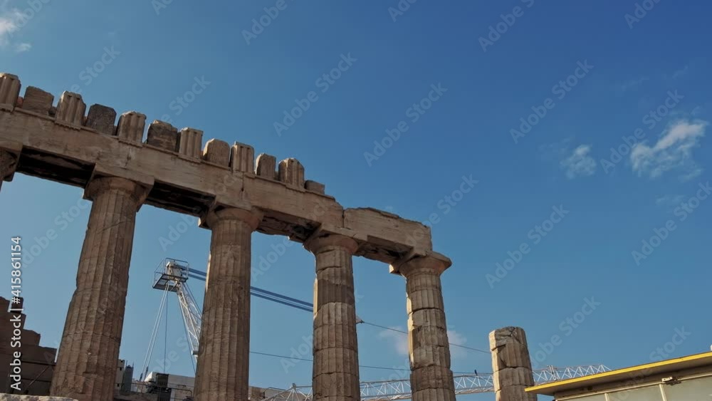 Tilt up shot of old acropolis building in Athens against blue sky. Crane and construction site for reconstruction in background. Tilt up shot of old acropolis building in Athens against blue sky. Crane and construction site for reconstruction in background.