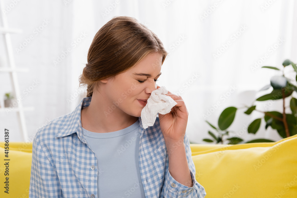 Young woman with napkin having snuffle during allergy Young woman with napkin having snuffle during allergy