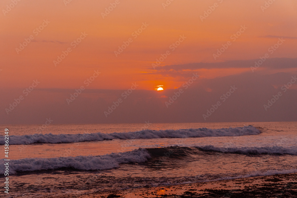 Pomarańczowo fioletowe niebo z zachodzącym słońcem, tropikalny krajobraz wybrzeże z oceanem.