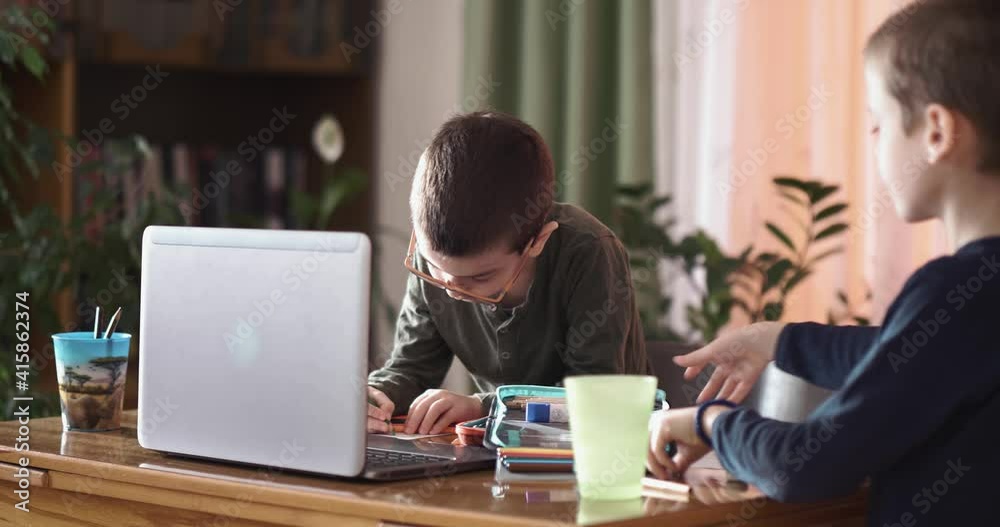 Two little boys brothers finish online school class at home, packing school supplies, education at home, virtual classroom Two little boys brothers finish online school class at home, packing school supplies, education at home, virtual classroom