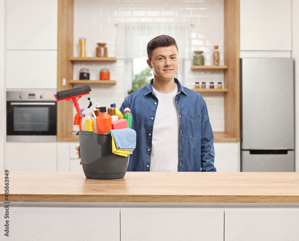 Guy in a kitchen posing with a bucket full of cleaning supplies Guy in a kitchen posing with a bucket full of cleaning supplies