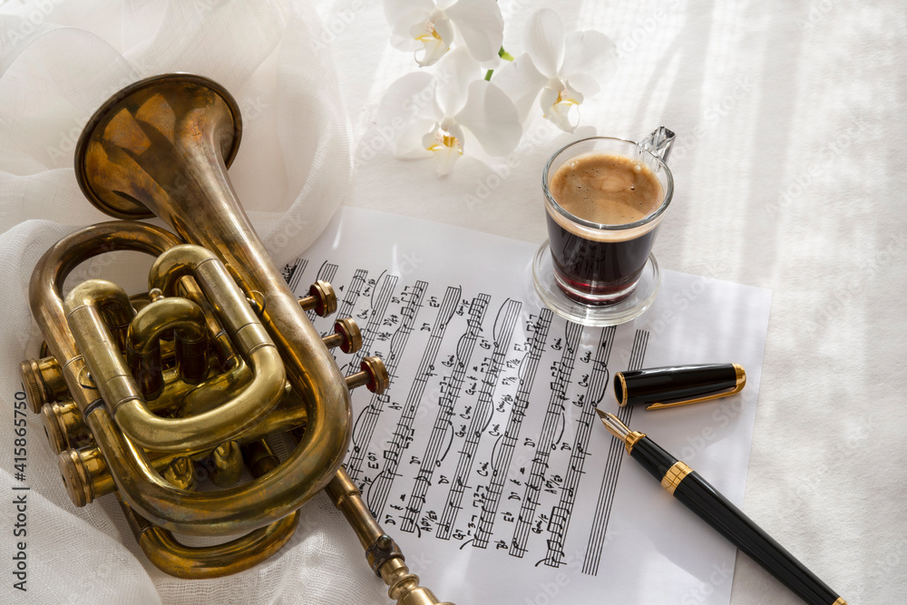 Naklejka premium Black coffee cup on a music score with trumpet and flower