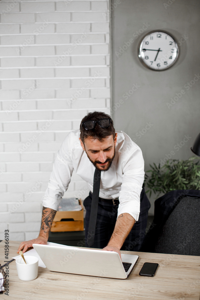 Young businessman using laptop in his office. Happy man working on computer at his workplace.. Young businessman using laptop in his office. Happy man working on computer at his workplace..