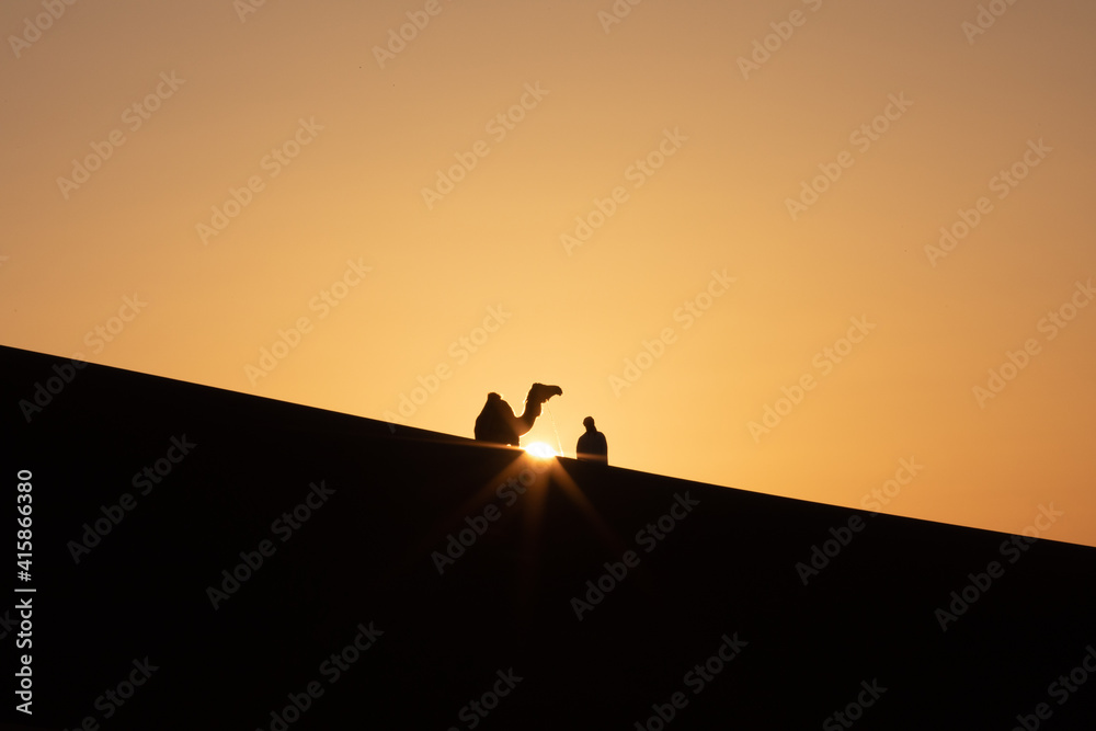 Silhouette of a nomad man with his camel in sand dunes at sunset. Liwa desert, Abu Dhabi, UAE. Silhouette of a nomad man with his camel in sand dunes at sunset. Liwa desert, Abu Dhabi, UAE.