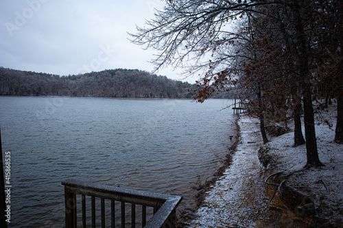 Joe Wheeler lake Alabama in winter overlooking shoreline of trees and mountain with snow and frost from dock. © Jon