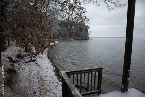coastline of lake in alabama during snow storm with trees, waves, boat dock, mountains © Jon