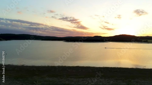 jet ski cruising on a lake while the sunsets behind rolling hills photo