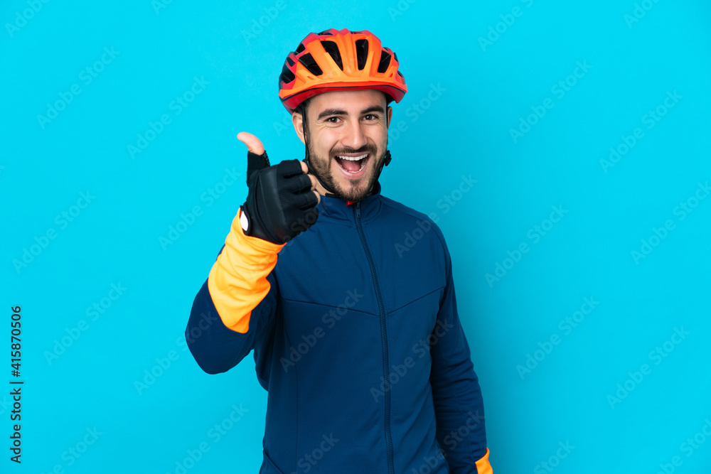 Young cyclist man isolated on blue background with thumbs up because something good has happened Young cyclist man isolated on blue background with thumbs up because something good has happened