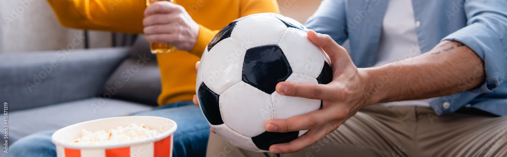 cropped view of man holding soccer ball near son on blurred background, banner
