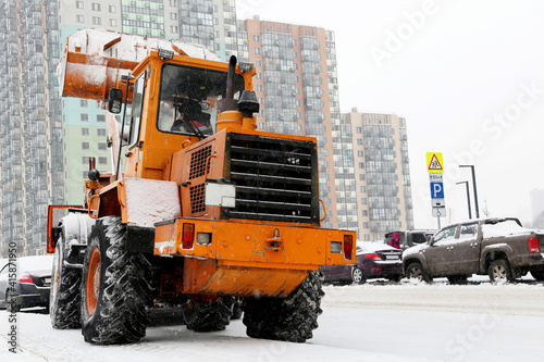 Snow plow machine on the road, street cleaning in winter city
