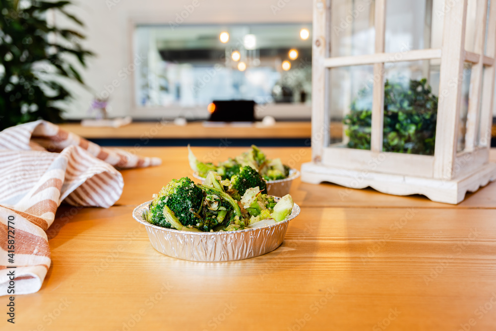 Broccoli and vegetables in an aluminum box on a wooden table. Vegan restaurant. Healthy lifestyle Broccoli and vegetables in an aluminum box on a wooden table. Vegan restaurant. Healthy lifestyle