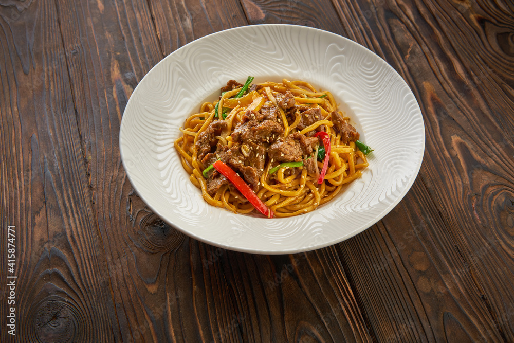 Delicious and spicy homemade noodle in white plate with black chopsticks on wooden table, asian food concept copy space for menu design Delicious and spicy homemade noodle in white plate with black chopsticks on wooden table, asian food concept copy space for menu design