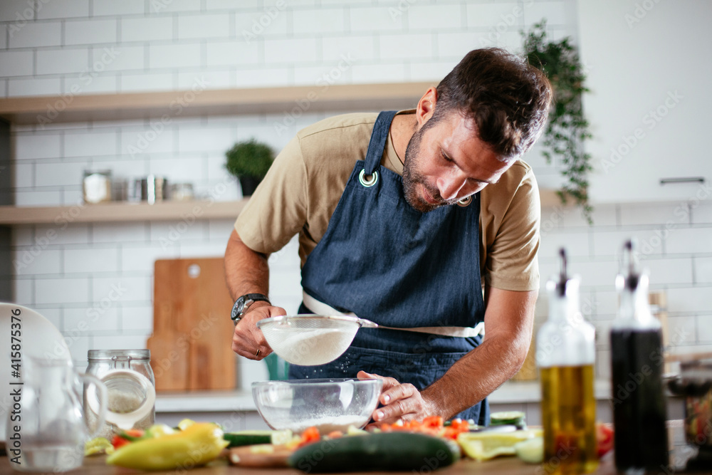 Happy man baking in the kitchen. Man making fresh pasta at home.