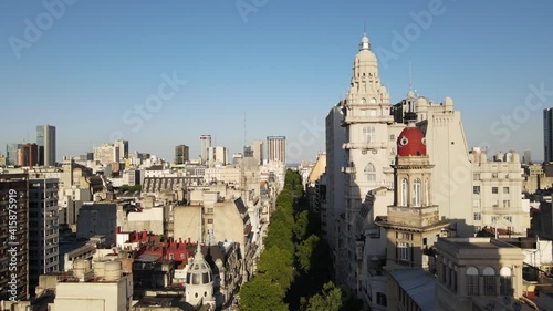 Aerial dolly in of tree-lined May Avenue and Barolo Palace tower at sunset in Monserrat neighborhood, Buenos Aires photo