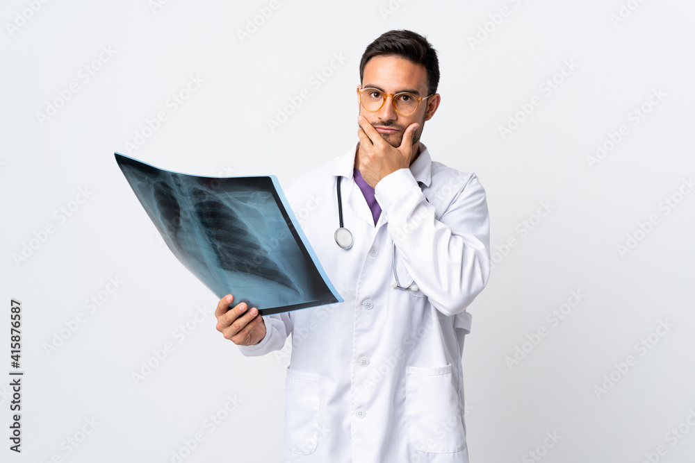 Young doctor man holding a radiography isolated on white background thinking an idea Young doctor man holding a radiography isolated on white background thinking an idea