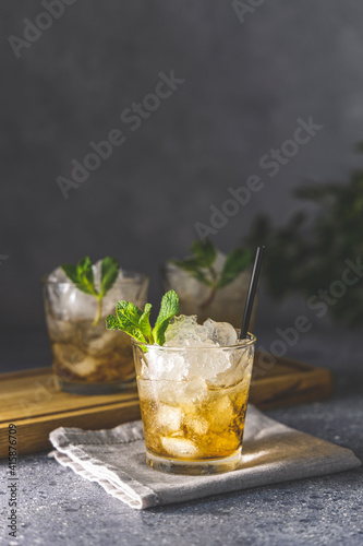 Close up of a mint julep served on light gray table surface and garnished with fresh green mint on top, kentucky derby drink