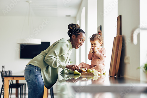 Foto Smiling mom and her cute little daughter eating a healthy snack