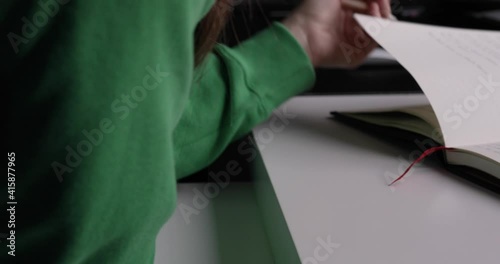 A woman turning pages of a notepad while calmly reading it