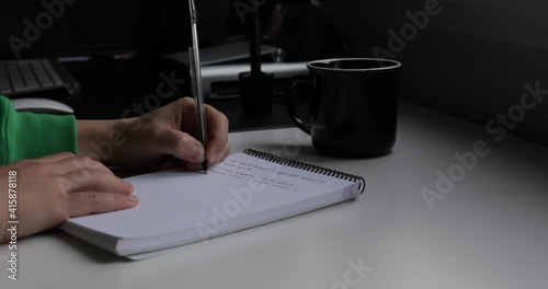 A left handed woman taking notes in a memo pad.
