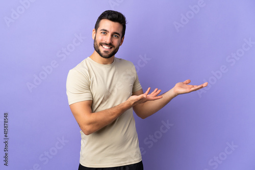 Young handsome man with beard over isolated background extending hands to the side for inviting to come