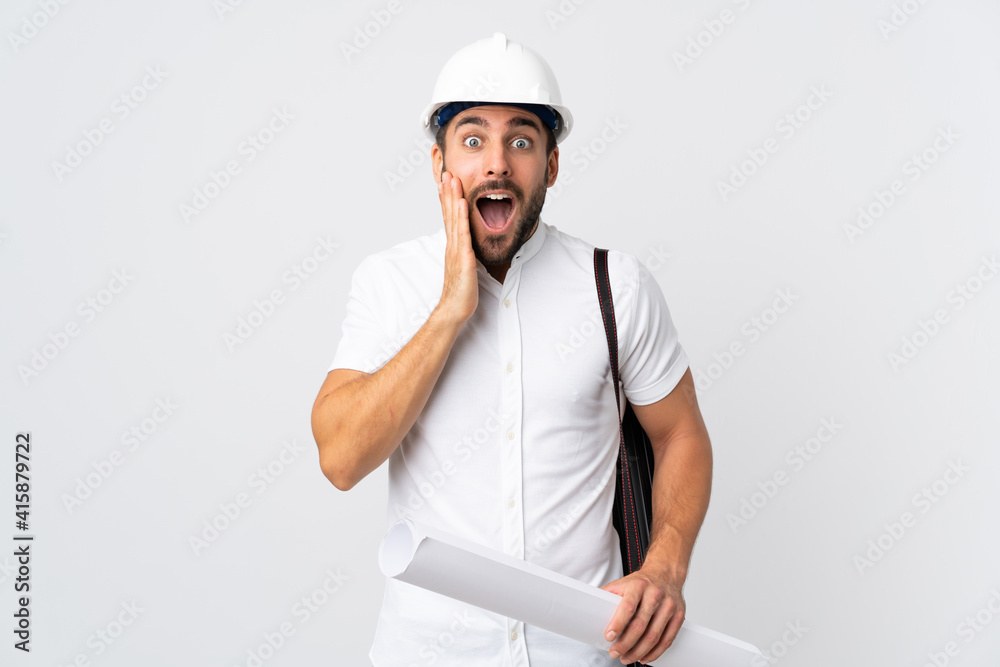 Young architect man with helmet and holding blueprints isolated on white background with surprise and shocked facial expression Young architect man with helmet and holding blueprints isolated on white background with surprise and shocked facial expression