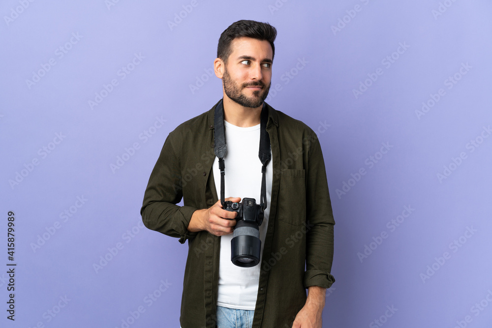 Naklejka premium Photographer man over isolated purple background having doubts while looking side