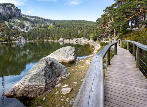 Wooden path around the glacial lake wtih mountain reflected in Laguna Negra in Urbion Glaciar Circos Natural Park, Soria, Castilla León, Spain photo