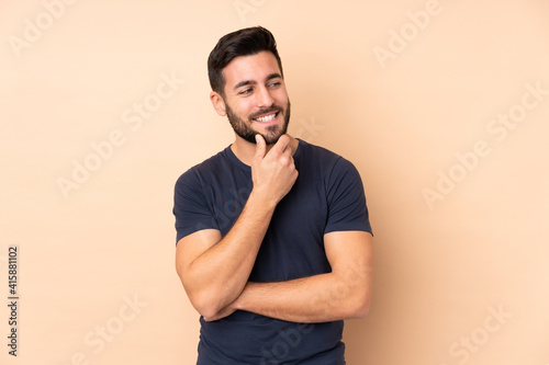 Caucasian handsome man isolated on beige background looking to the side and smiling