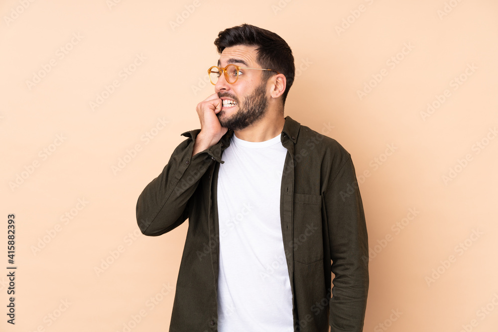 Caucasian handsome man isolated on beige background is a little bit nervous Caucasian handsome man isolated on beige background is a little bit nervous