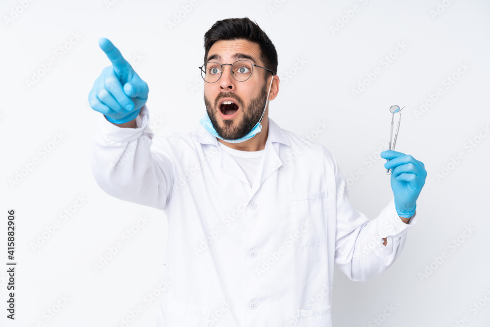 Dentist man holding tools isolated on white background pointing away Dentist man holding tools isolated on white background pointing away