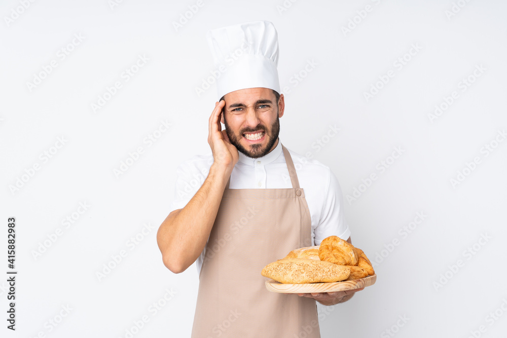 Male baker holding a table with several breads isolated on white background unhappy and frustrated with something. Negative facial expression Male baker holding a table with several breads isolated on white background unhappy and frustrated with something. Negative facial expression