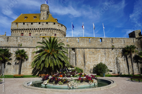 old stone castle in the town of St Malo, Brittany, France with palm trees and flower beds