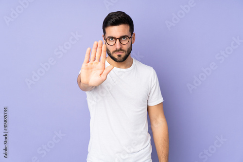 Caucasian handsome man over isolated background making stop gesture
