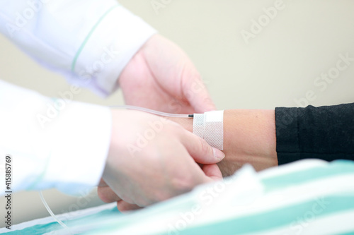 A female nurse is fixing the needle of the infusion set in the ward