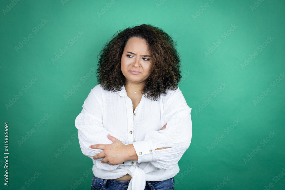 Young african american girl wearing white shirt over green background thinking looking tired and bored with crossed arms Young african american girl wearing white shirt over green background thinking looking tired and bored with crossed arms