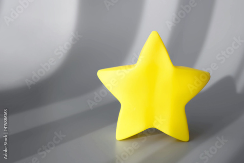 Yellow star on gray background with shadows. Trendy Color of Year 2021. Illuminating Yellow and Ultimate Gray. Copy space. Creative minimal easter concept. Flat lay.