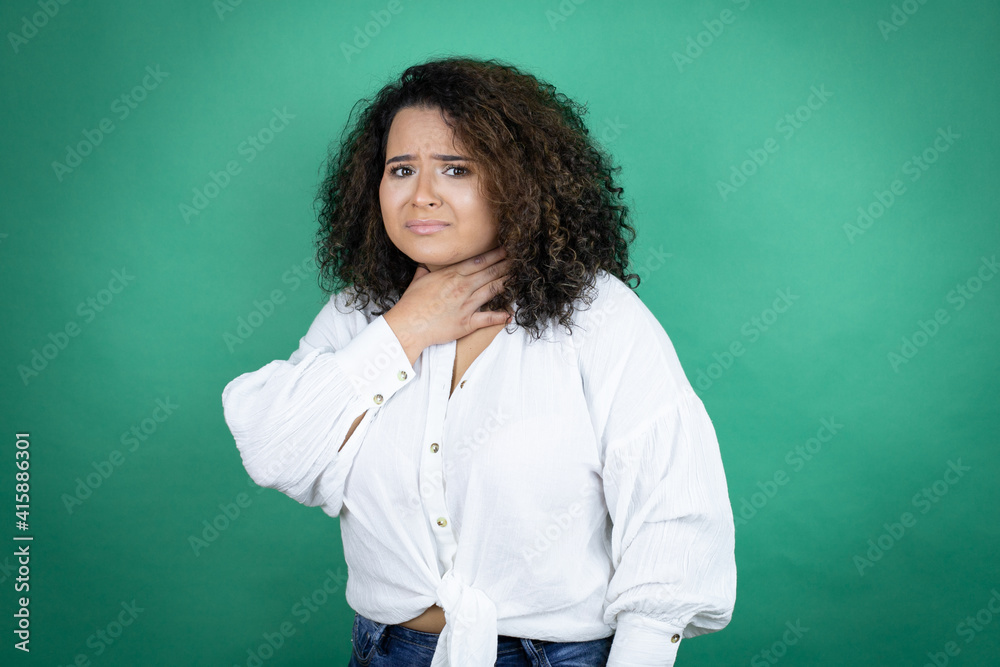Young african american girl wearing white shirt over green background touching painful neck, sore throat for flu, clod and infection Young african american girl wearing white shirt over green background touching painful neck, sore throat for flu, clod and infection