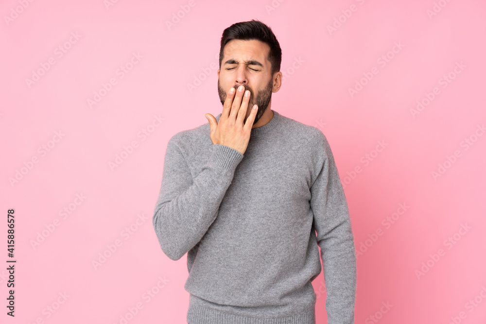 Caucasian handsome man over isolated background yawning and covering wide open mouth with hand Caucasian handsome man over isolated background yawning and covering wide open mouth with hand