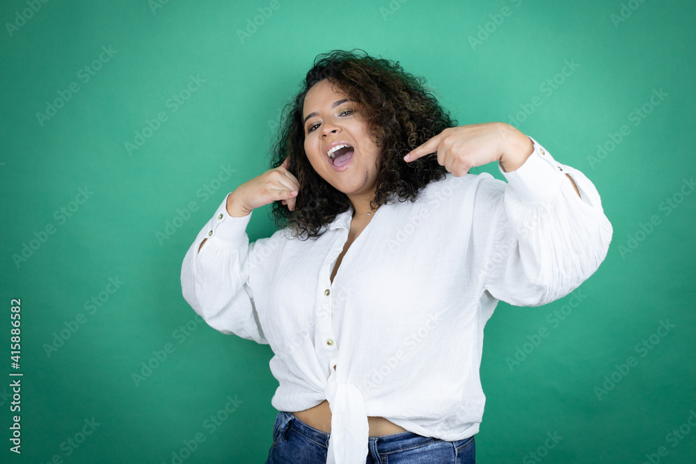 Young african american girl wearing white shirt over green background doing the “call me” gesture with her hands.