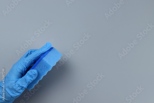 Sponge in a gloved hand on a gray background